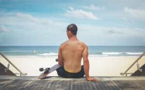 Photograph of a skateboarder sitting on the steps above an Australian beach.